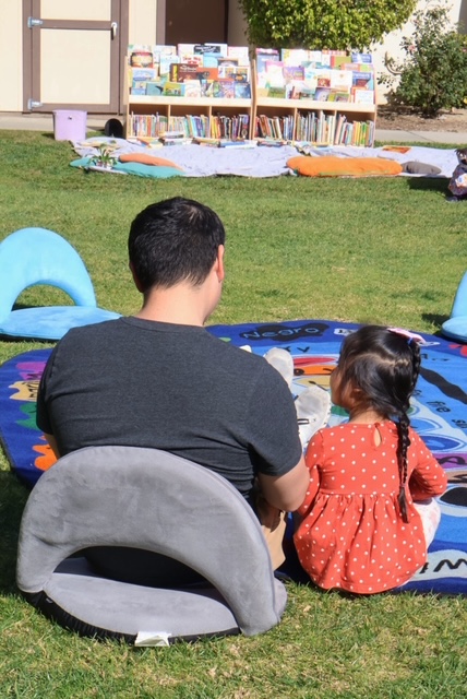 man and a little girl sitting on mat