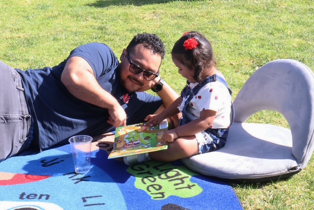 man lying on mat with and a little girl sitting