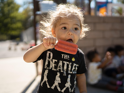 A kid licking ice popsicle. 