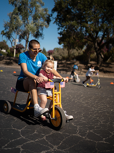 A kid and adult riding a bike.